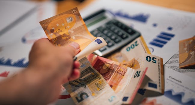 Close-up of Euro banknotes on financial documents and a calculator, depicting financial planning. dans la page aides.